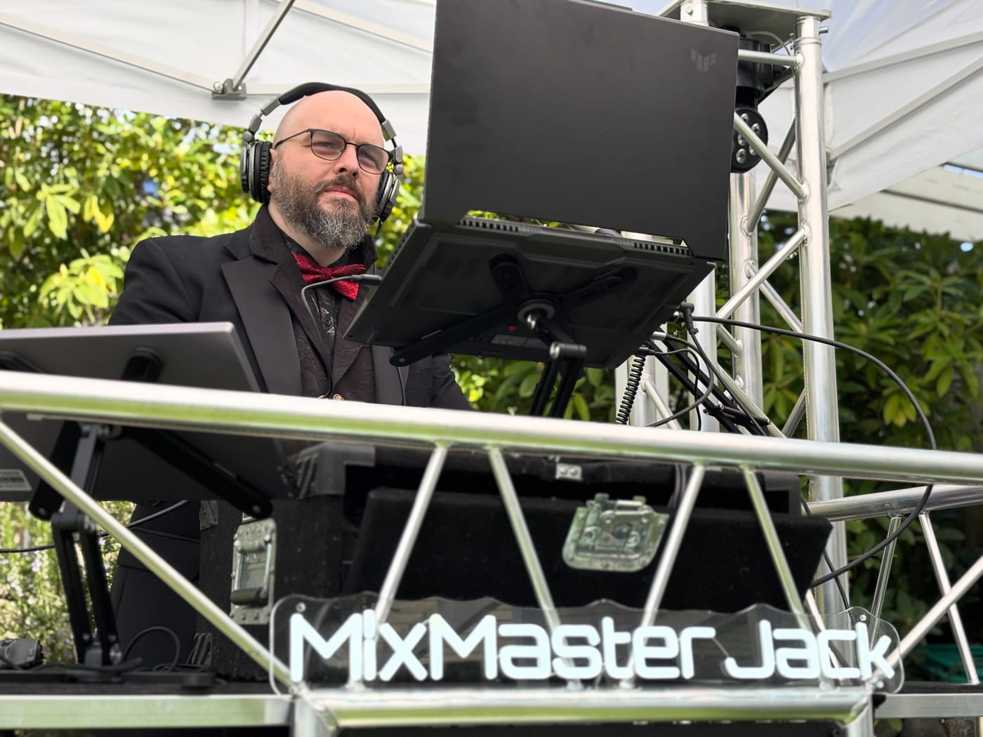 MixMaster Jack performing at an outdoor event behind his branded DJ booth